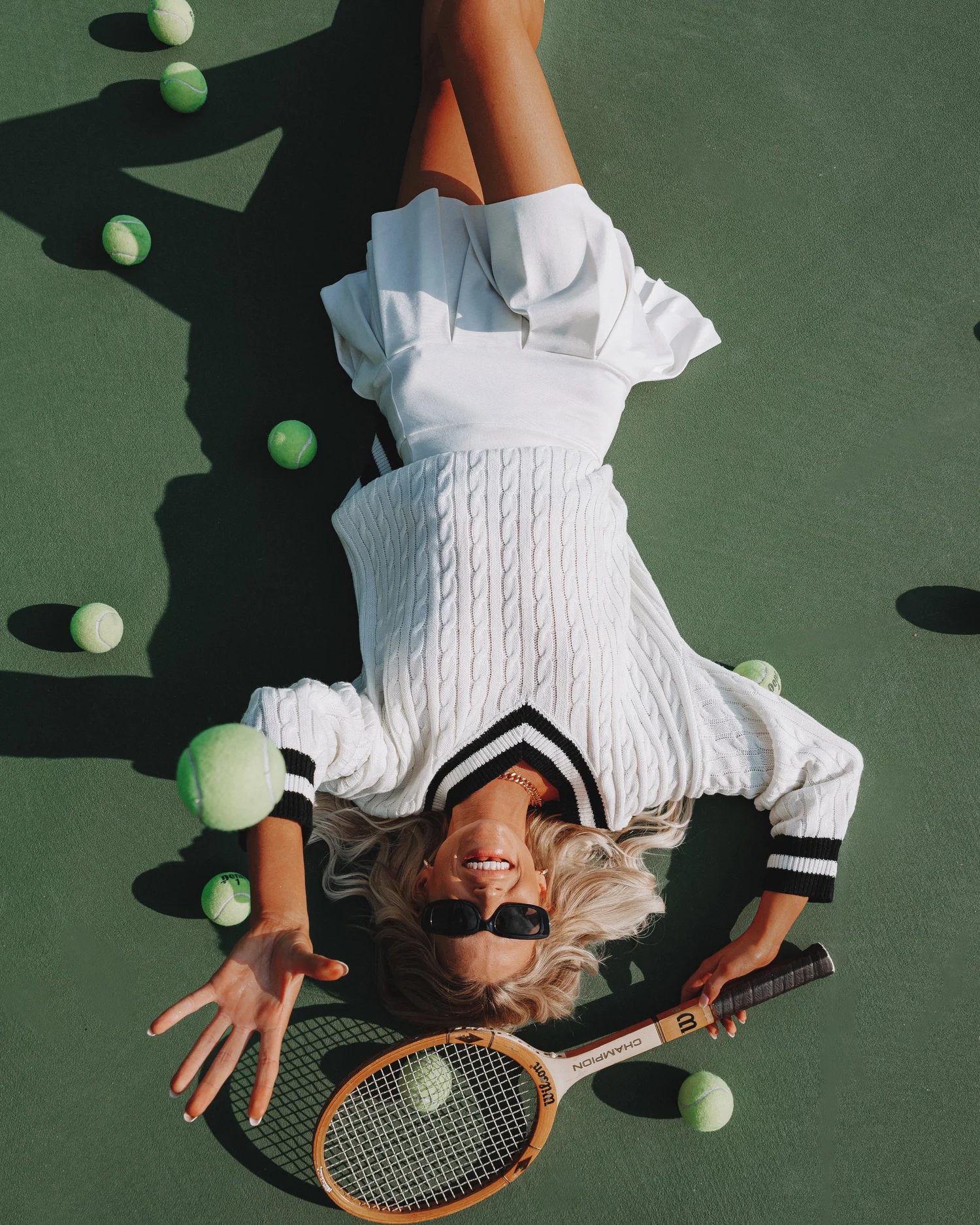 Fashion image on tennis court with sweater and racket